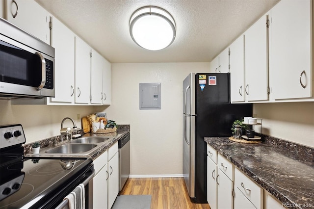 kitchen with sink, a textured ceiling, electric panel, stainless steel appliances, and white cabinets