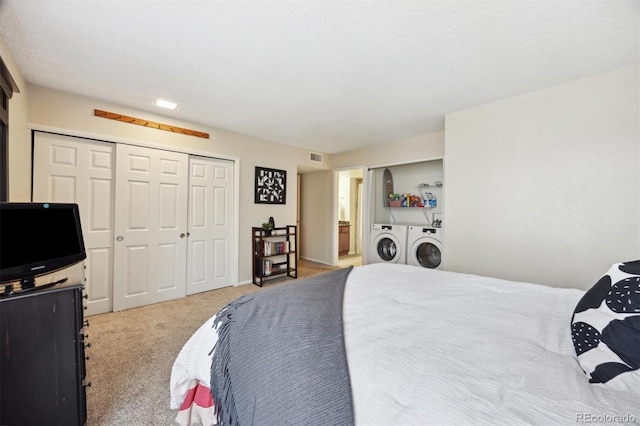 bedroom featuring light carpet, a textured ceiling, independent washer and dryer, and a closet