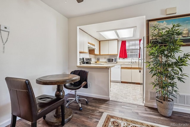 kitchen with sink, white cabinets, dark hardwood / wood-style flooring, kitchen peninsula, and stainless steel appliances