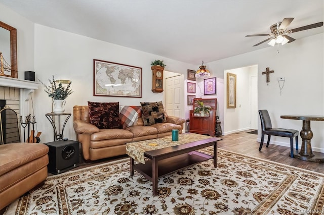 living room with ceiling fan, hardwood / wood-style floors, and a brick fireplace