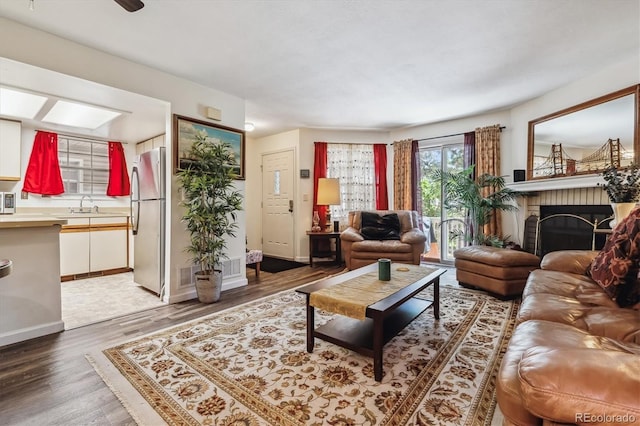 living room featuring dark wood-type flooring, sink, and a brick fireplace