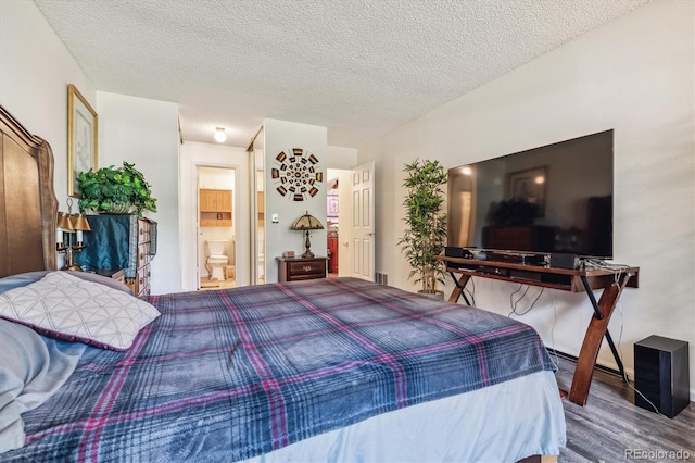 bedroom with connected bathroom, hardwood / wood-style floors, and a textured ceiling