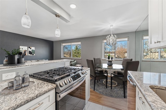 kitchen featuring a chandelier, stainless steel appliances, white cabinets, light stone countertops, and pendant lighting