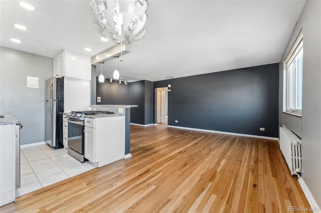 kitchen featuring white cabinetry, radiator heating unit, appliances with stainless steel finishes, and baseboards