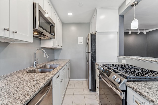 kitchen with light stone counters, white cabinetry, stainless steel appliances, and a sink