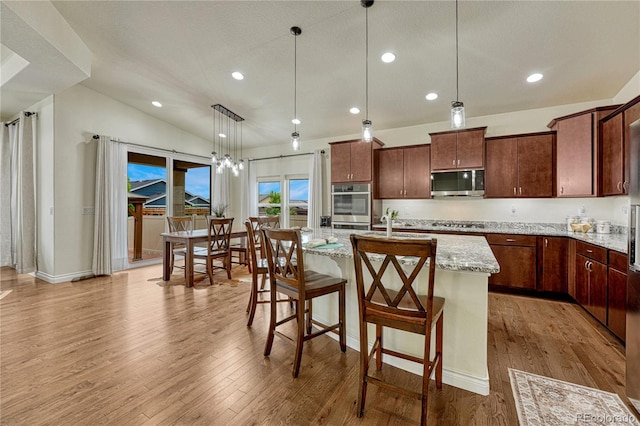 13190 Stone Peaks Way, Peyton, CO 80831 - kitchen with appliances with stainless steel finishes, a kitchen island with sink, light wood finished floors, light stone countertops, and recessed lighting
