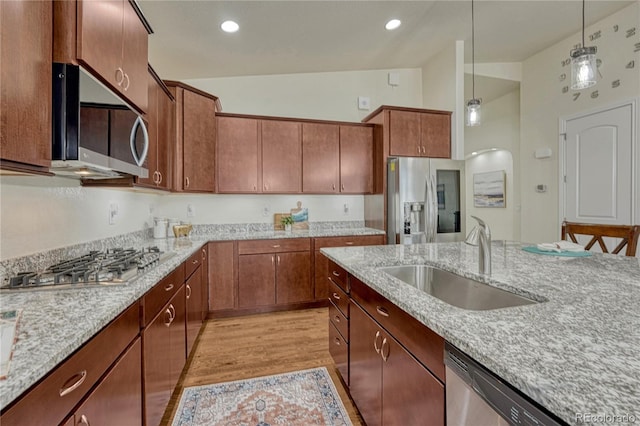 13190 Stone Peaks Way, Peyton, CO 80831 - kitchen with appliances with stainless steel finishes, decorative light fixtures, light stone counters, high vaulted ceiling, and light wood-style floors