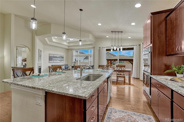 13190 Stone Peaks Way, Peyton, CO 80831 - kitchen with light wood-type flooring, a kitchen island with sink, recessed lighting, stainless steel appliances, and decorative light fixtures