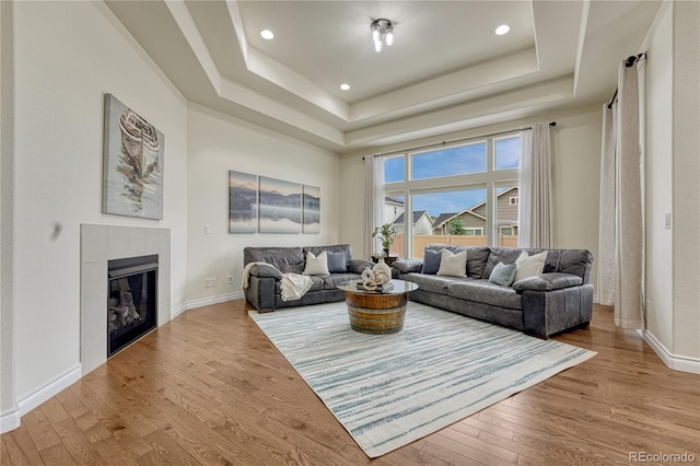 13190 Stone Peaks Way, Peyton, CO 80831 - living room featuring wood finished floors, a tray ceiling, a fireplace, and recessed lighting