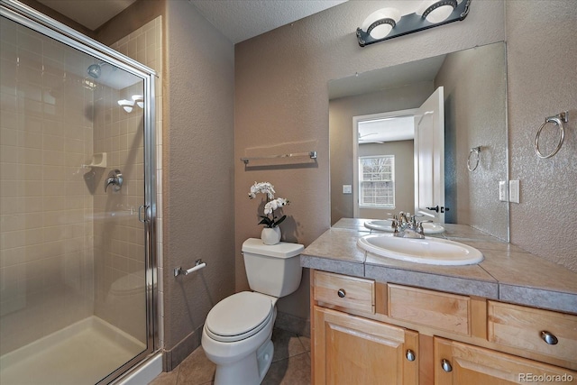 bathroom with tile patterned flooring, vanity, toilet, a shower with shower door, and a textured ceiling