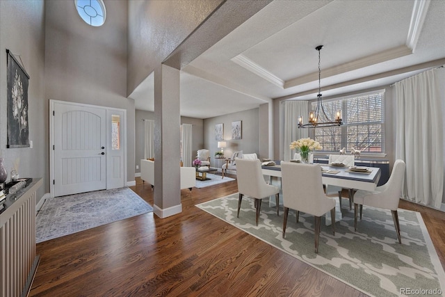 dining space with a tray ceiling, dark hardwood / wood-style flooring, a chandelier, and a textured ceiling