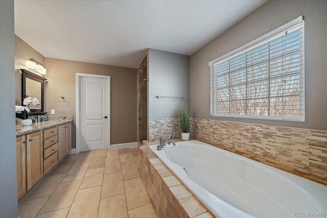 bathroom featuring tiled tub, vanity, and tile patterned flooring