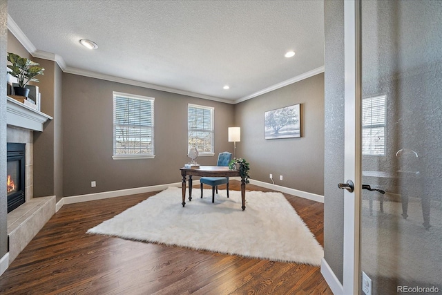 office space with a tiled fireplace, dark wood-type flooring, a textured ceiling, and ornamental molding