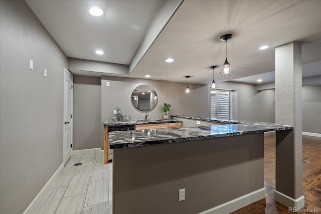 kitchen featuring dark stone counters, decorative light fixtures, dishwasher, kitchen peninsula, and light hardwood / wood-style floors