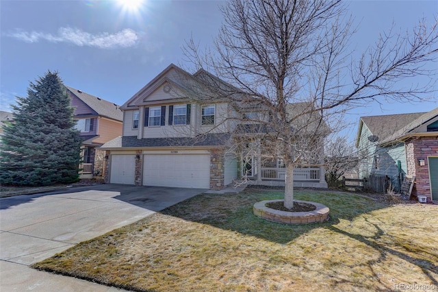 traditional home with stone siding, a front yard, concrete driveway, and an attached garage