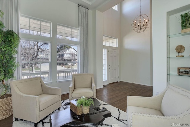 interior space with plenty of natural light, a high ceiling, an inviting chandelier, and wood finished floors