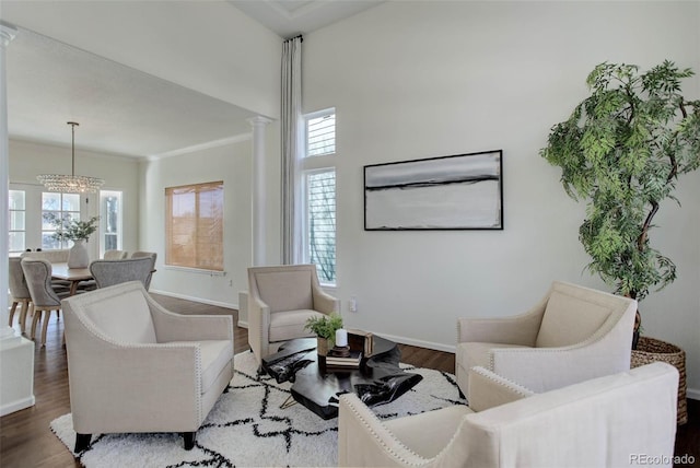 living area featuring a wealth of natural light, a notable chandelier, baseboards, and wood finished floors