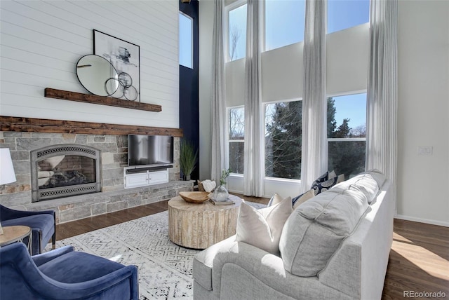 living area featuring a wealth of natural light, a high ceiling, baseboards, and wood finished floors