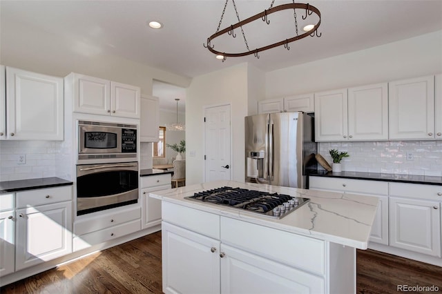 kitchen featuring decorative backsplash, white cabinets, appliances with stainless steel finishes, and dark wood-style flooring