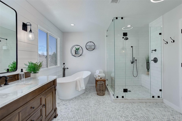 bathroom with baseboards, recessed lighting, a stall shower, a freestanding tub, and vanity