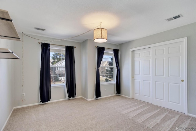 unfurnished bedroom with visible vents, light colored carpet, and baseboards