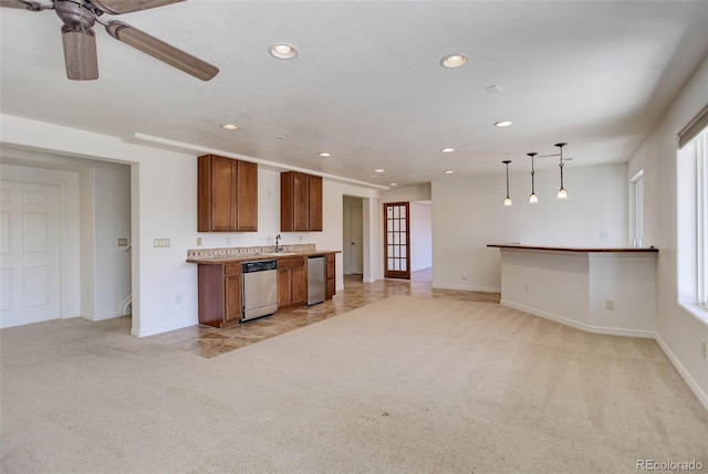 kitchen with dishwasher, a ceiling fan, brown cabinetry, and light carpet