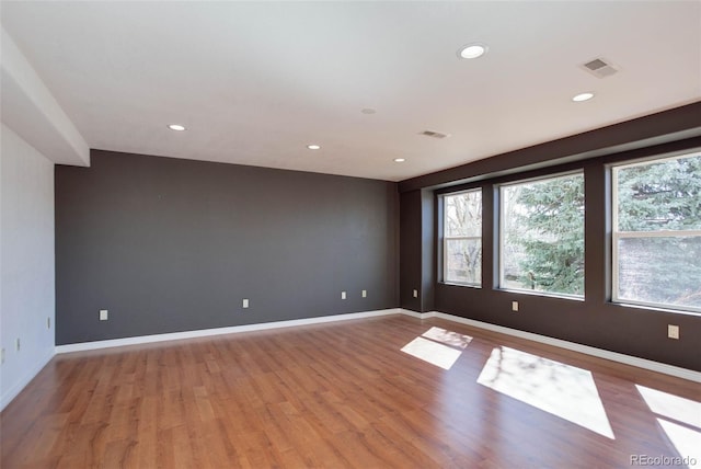 unfurnished room with light wood-style flooring, plenty of natural light, and visible vents