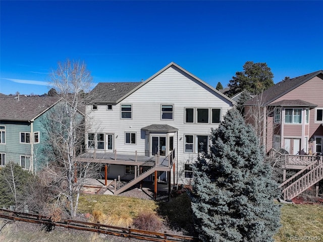 back of property with a lawn, a shingled roof, stairs, and a deck