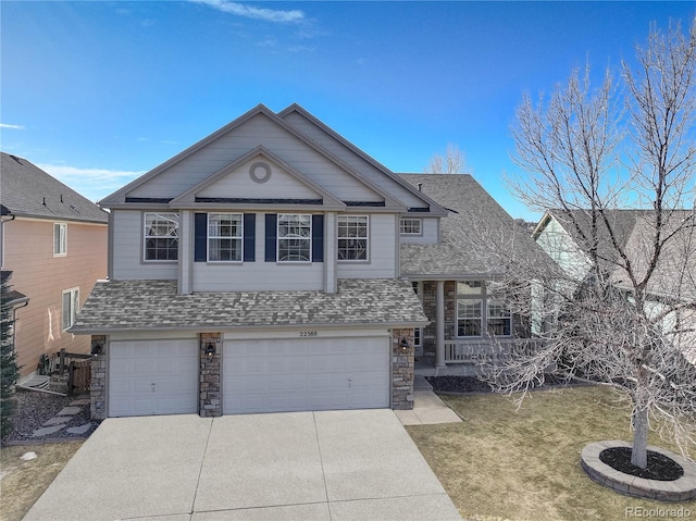 view of front facade featuring a front yard, roof with shingles, concrete driveway, a garage, and stone siding