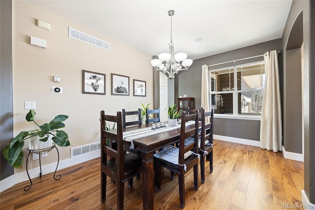 dining area with light wood-style floors, visible vents, and a notable chandelier