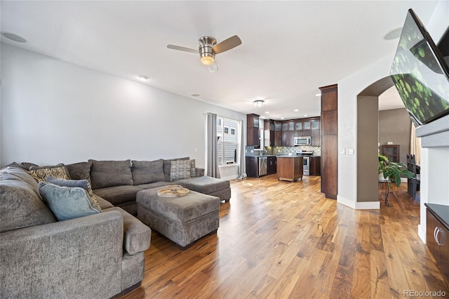 living room with a ceiling fan, arched walkways, light wood finished floors, and recessed lighting