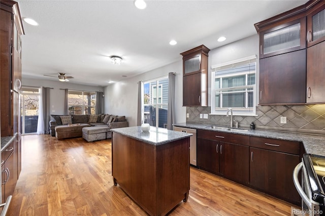 kitchen with a center island, decorative backsplash, appliances with stainless steel finishes, a sink, and light wood-type flooring