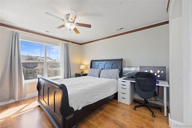 bedroom with ceiling fan, ornamental molding, wood finished floors, and visible vents