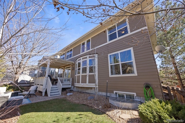 rear view of property with a wooden deck, fence, a lawn, and a patio