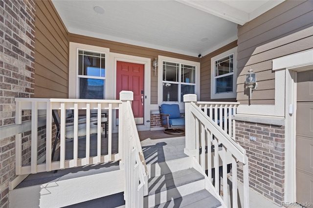 property entrance featuring covered porch and brick siding