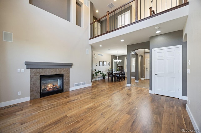 unfurnished living room featuring arched walkways, visible vents, baseboards, and wood finished floors