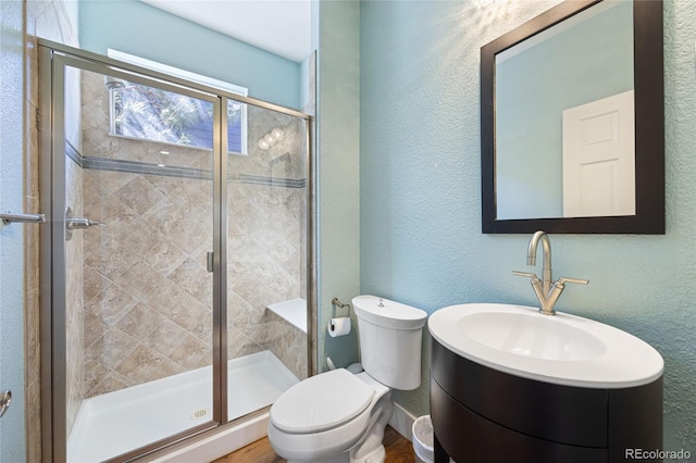 full bathroom with a stall shower, a sink, a textured wall, and toilet