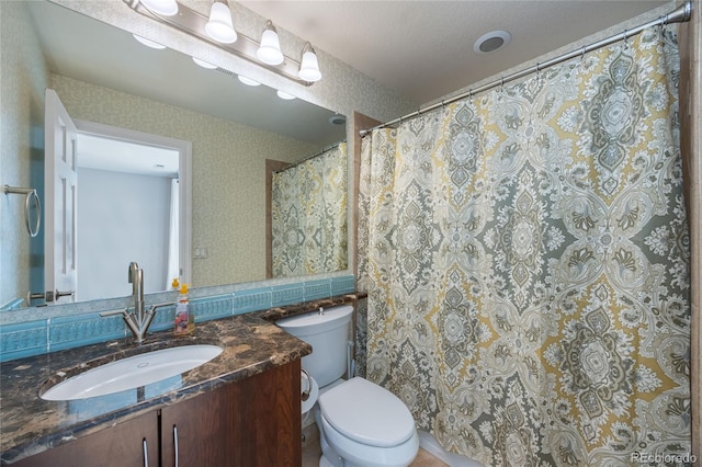 bathroom with toilet, vanity, and wallpapered walls