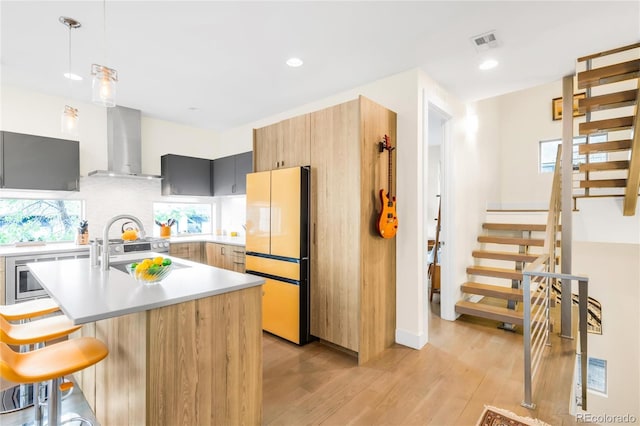 1333 Elati St Unit 1, Denver, CO 80204 - kitchen featuring visible vents, light countertops, freestanding refrigerator, light wood-style floors, and wall chimney exhaust hood