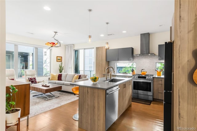 1333 Elati St Unit 1, Denver, CO 80204 - kitchen with wall chimney range hood, modern cabinets, wood finished floors, a sink, and stainless steel appliances