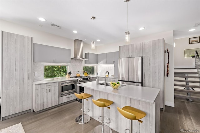 1333 Elati St Unit 1, Denver, CO 80204 - kitchen featuring stainless steel appliances, wall chimney range hood, a kitchen breakfast bar, light countertops, and recessed lighting