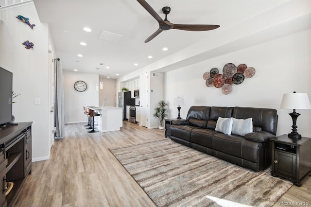 living room with light hardwood / wood-style flooring and ceiling fan