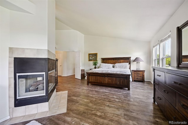 5465 Broadmoor Bliff Dr, Colorado Springs, CO 80904 - bedroom featuring a tile fireplace, dark wood-style flooring, baseboards, and high vaulted ceiling