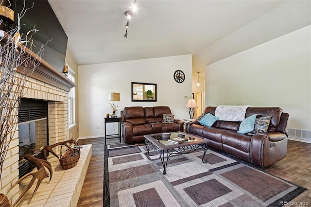 5465 Broadmoor Bliff Dr, Colorado Springs, CO 80904 - living room featuring vaulted ceiling, wood finished floors, baseboards, a brick fireplace, and rail lighting