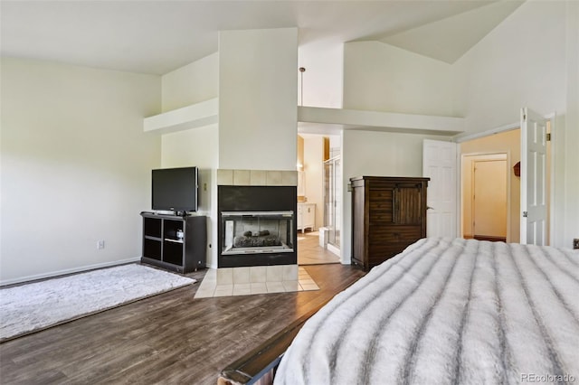 5465 Broadmoor Bliff Dr, Colorado Springs, CO 80904 - bedroom with high vaulted ceiling, wood finished floors, a tiled fireplace, baseboards, and ensuite bathroom