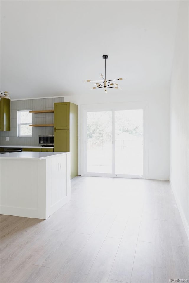 kitchen featuring green cabinetry, a notable chandelier, and backsplash