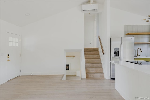 interior space featuring sink, wood-type flooring, a wall mounted AC, high vaulted ceiling, and a fireplace