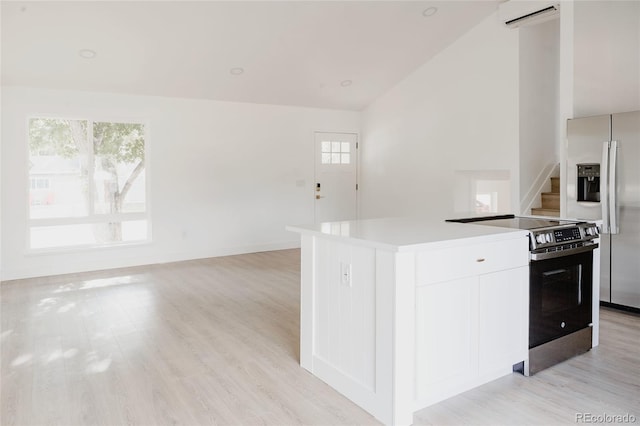 kitchen with light hardwood / wood-style flooring, appliances with stainless steel finishes, white cabinetry, a wall unit AC, and a kitchen island