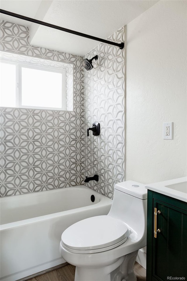 full bathroom featuring tiled shower / bath combo, vanity, and toilet