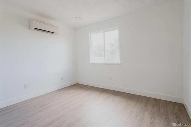 spare room featuring light hardwood / wood-style flooring and an AC wall unit